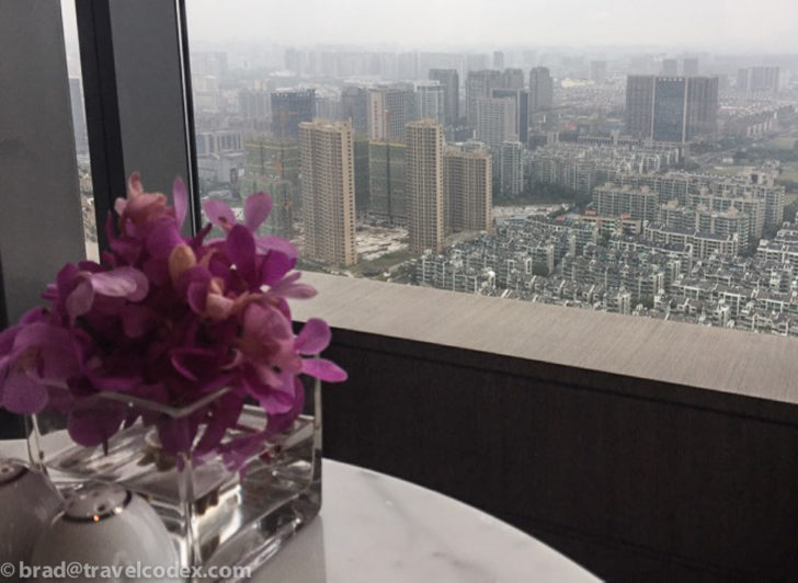 a vase with purple flowers in it and a city view from a window