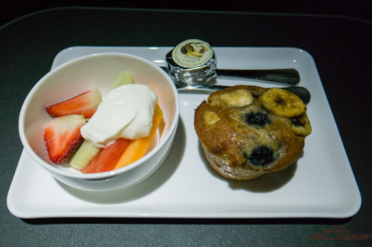 a plate with a bowl of fruit and a muffin