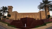 a building with a fountain and palm trees