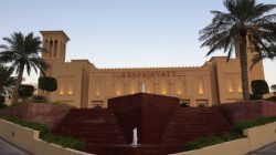 a building with a fountain and palm trees