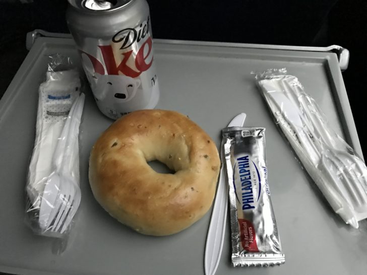 a bagel and soda on a tray