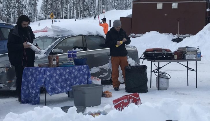 a man standing in the snow next to a car