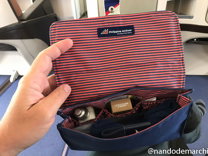a hand holding a blue and red striped bag with items inside