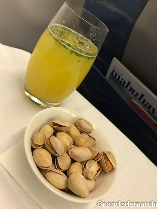 a bowl of pistachios and a drink