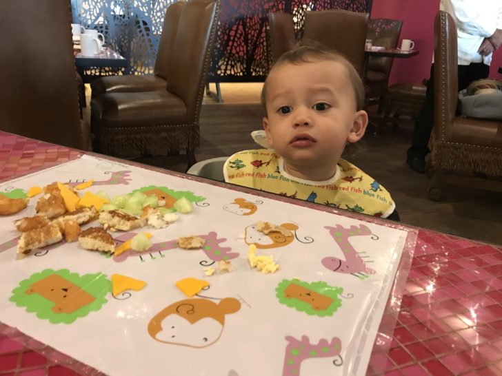 a baby sitting at a table with food on it