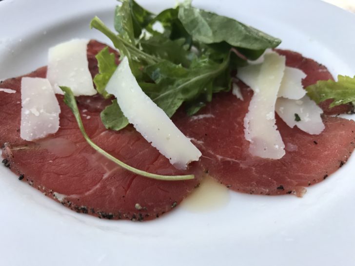 meat with cheese and greens on a white plate