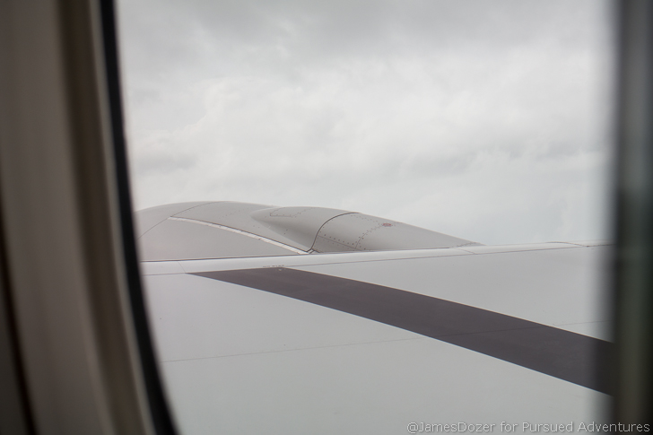 a plane wing with a cloudy sky