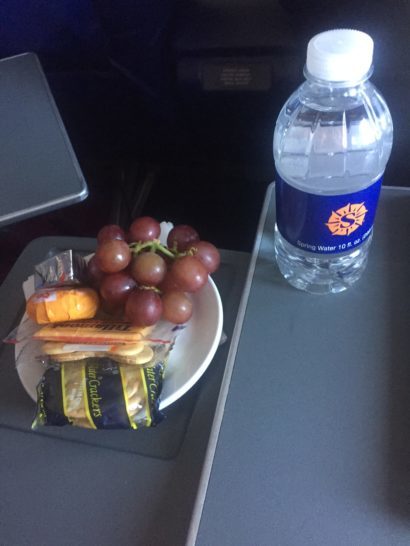 a plate of grapes and crackers next to a bottle of water