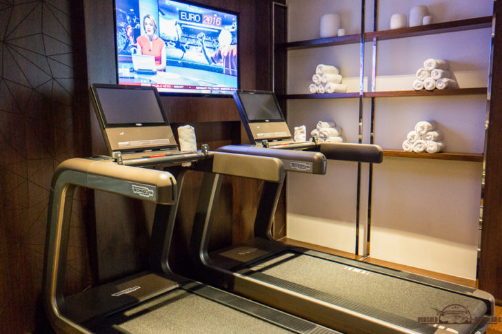 a treadmills with laptops and a tv on the wall
