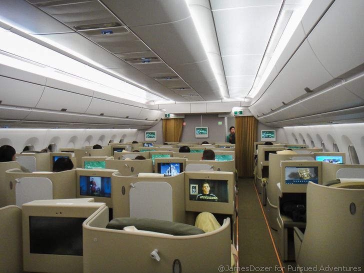 a plane with rows of monitors and people sitting on chairs