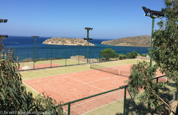 a tennis court with a body of water in the background