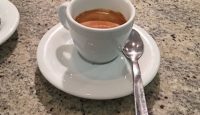 a cup of coffee on a saucer with a spoon