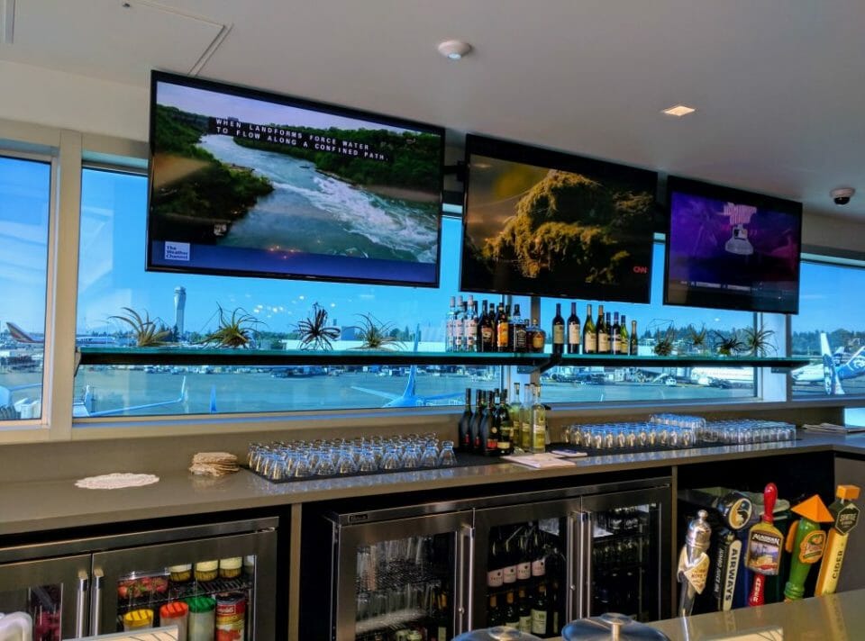 a bar with several screens and a view of a river