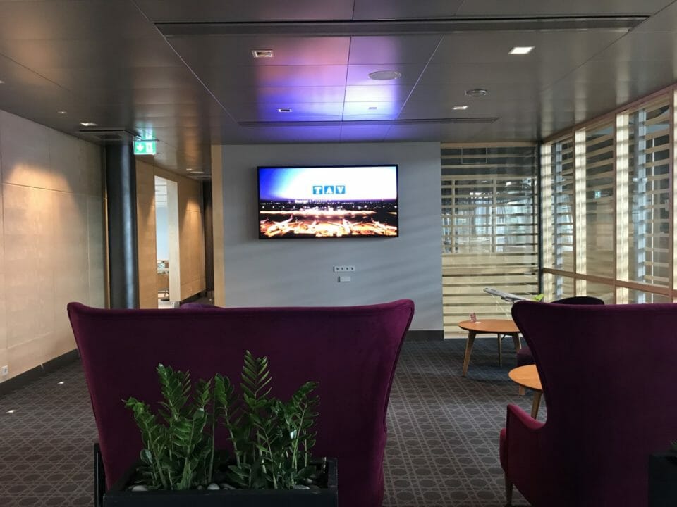 a room with purple chairs and a tv on the wall