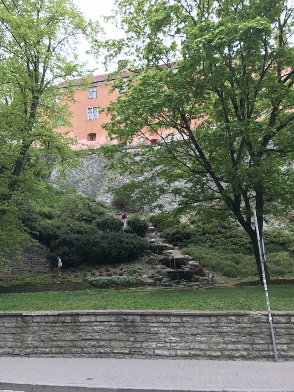 a stone wall with trees and a building in the background