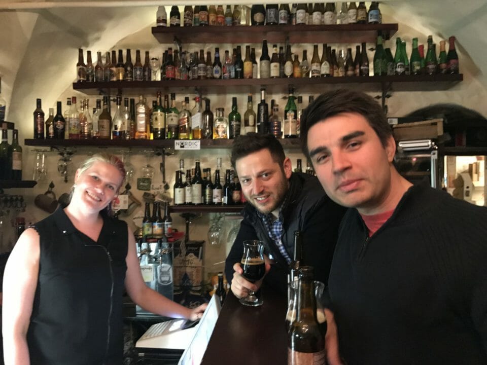 a group of people standing at a bar with bottles on shelves