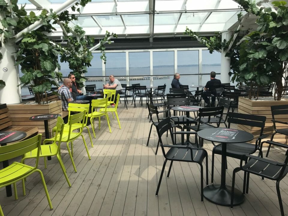 a group of people sitting at tables and chairs in a room with a glass roof