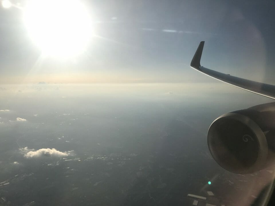 an airplane wing and sun in the sky