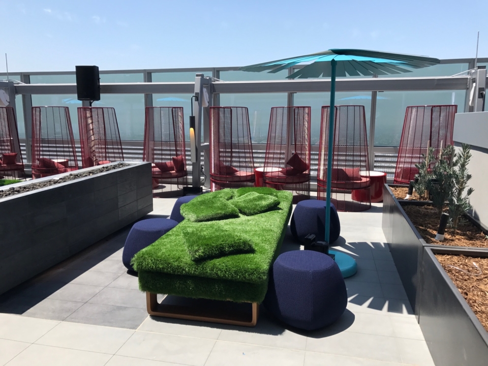 a green couch with blue and red chairs on a rooftop