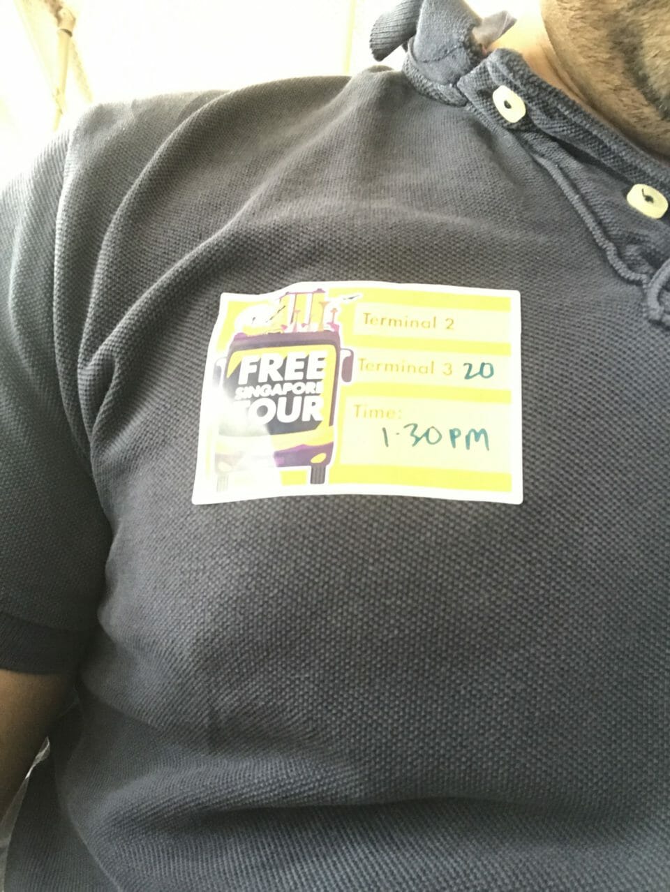 a person wearing a grey shirt with a sticker on it