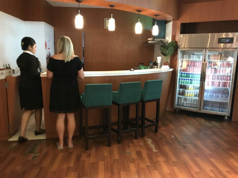 a woman standing at a counter in a room with chairs and a refrigerator