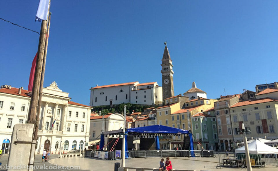 a group of people in a square with a clock tower in the background