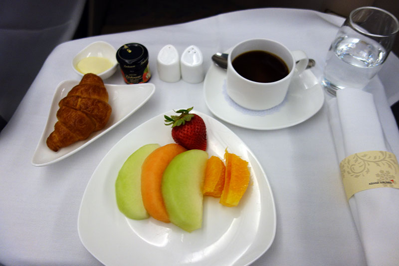 a plate of fruit and a croissant on a table