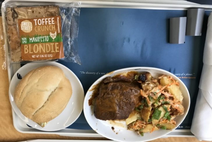 a plate of food and a bag of bread on a tray