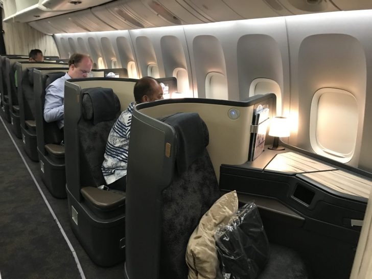 a group of men sitting in a row of seats on an airplane