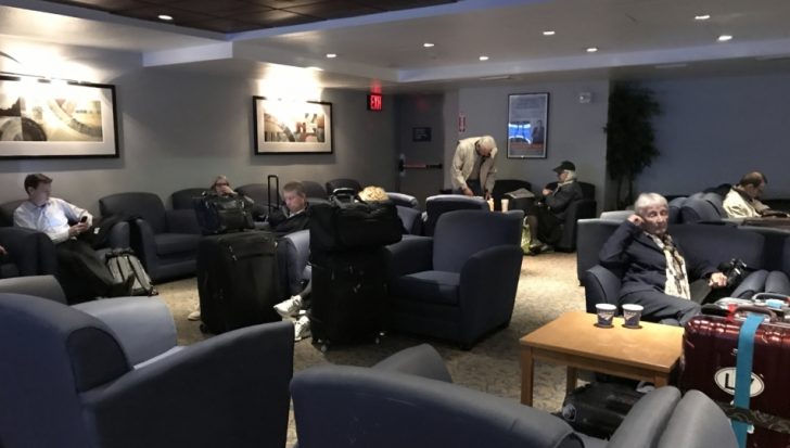 a group of people sitting in a room with chairs and luggage