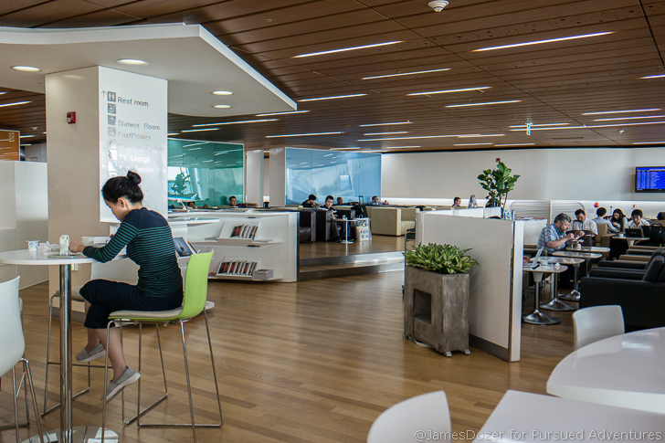 people sitting at tables in a room with white walls and wood floor