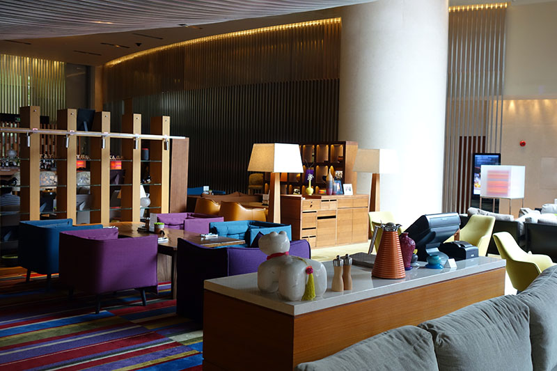 a room with a large column and a large table with purple chairs
