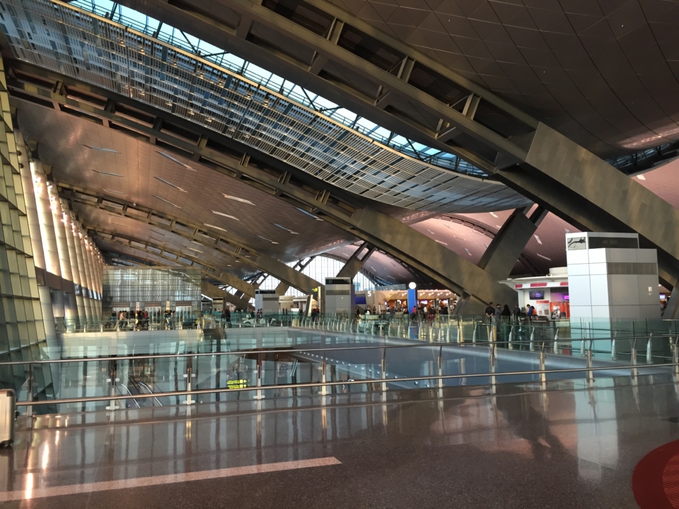 a large airport with glass walls and people walking