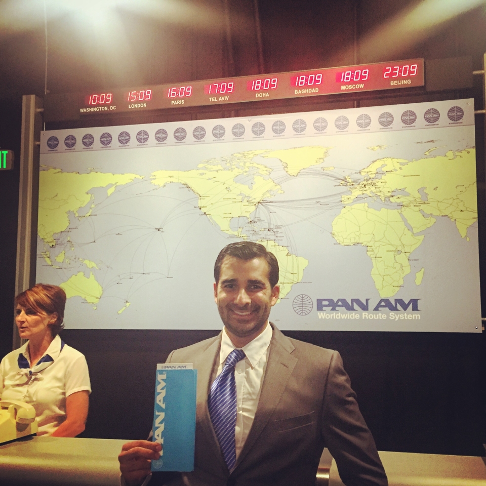 a man in a suit holding a blue book in front of a large world map