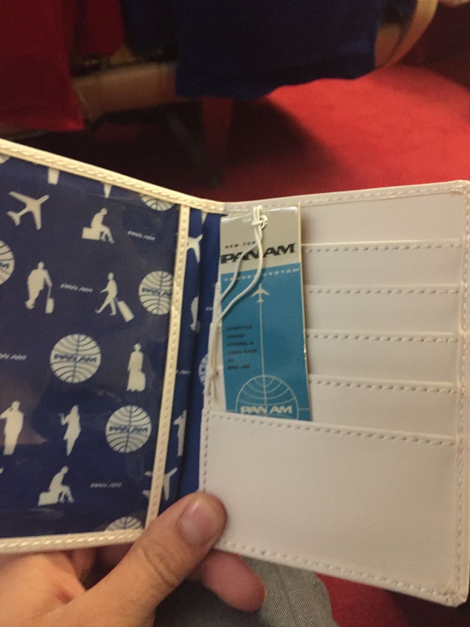 a hand holding a white wallet with a blue and white pattern