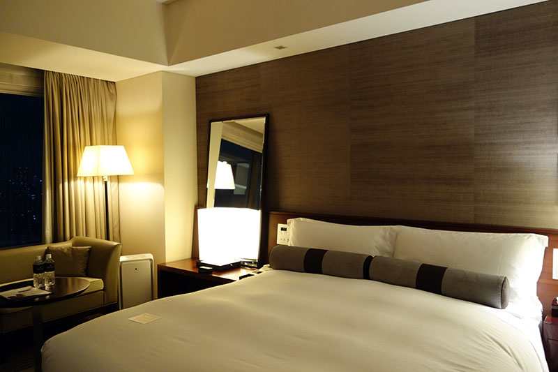 a bed with a lamp and a mirror