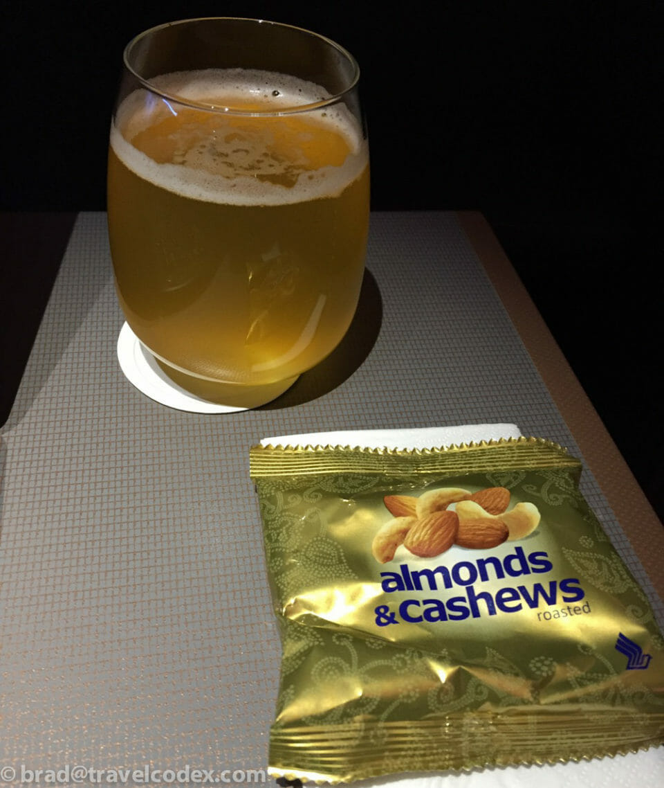 a glass of beer next to a bag of nuts