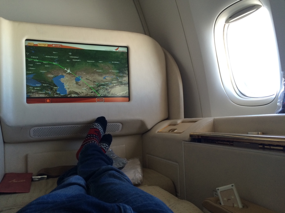 a person's legs in a chair with a television on the back of a plane