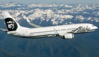 a white airplane flying over mountains