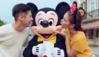 a man and woman kissing a person in a mouse garment