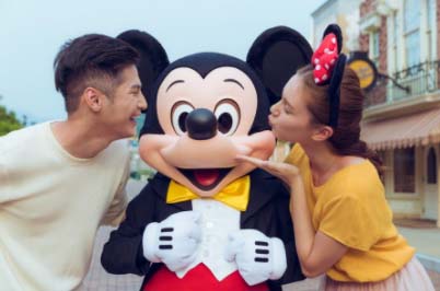 a man and woman kissing a person in a mouse garment