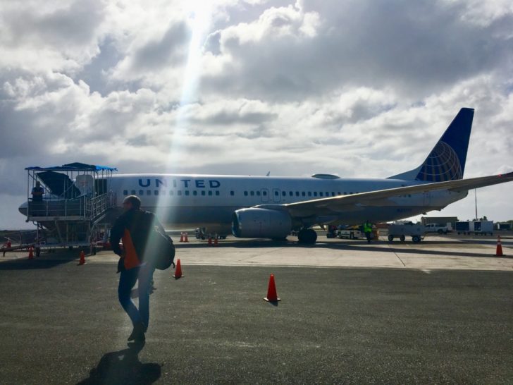 a man walking on a tarmac with a plane in the background