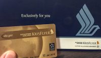 a hand holding a gold card next to a blue box