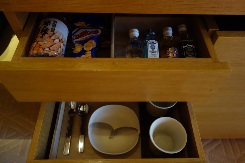 a drawer with a bowl and spoons and bottles