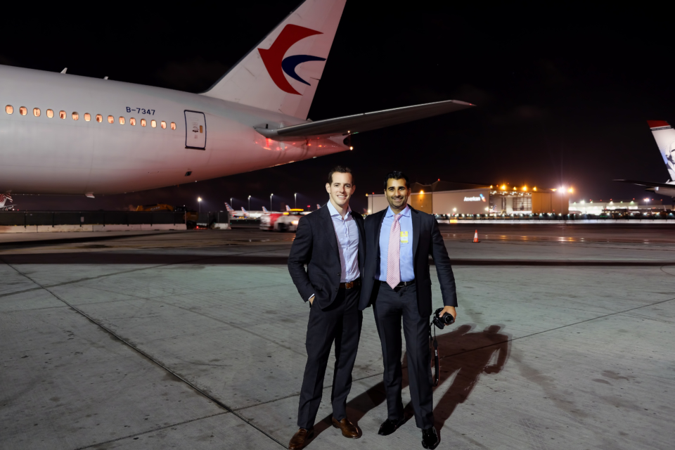 two men standing in front of an airplane