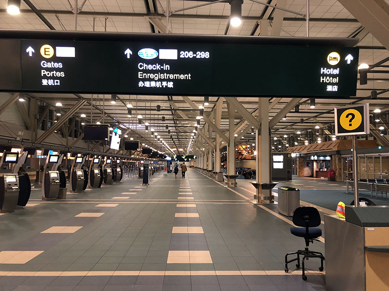 a large airport terminal with signs and people walking