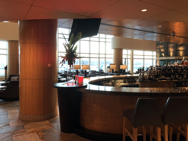 a bar with a counter and chairs in a room with windows