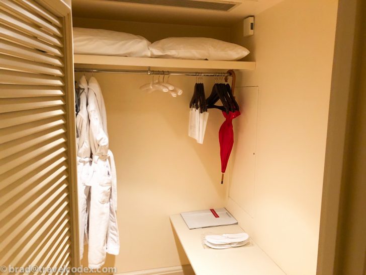 a closet with white towels and a red umbrella