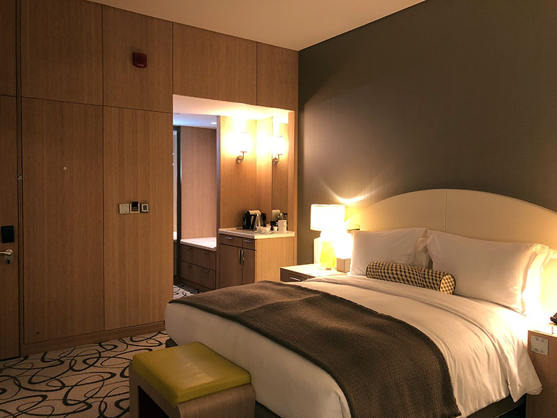 a bed with a white blanket and a yellow pillow