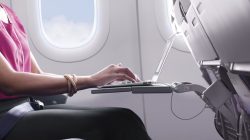 a woman using a laptop on an airplane
